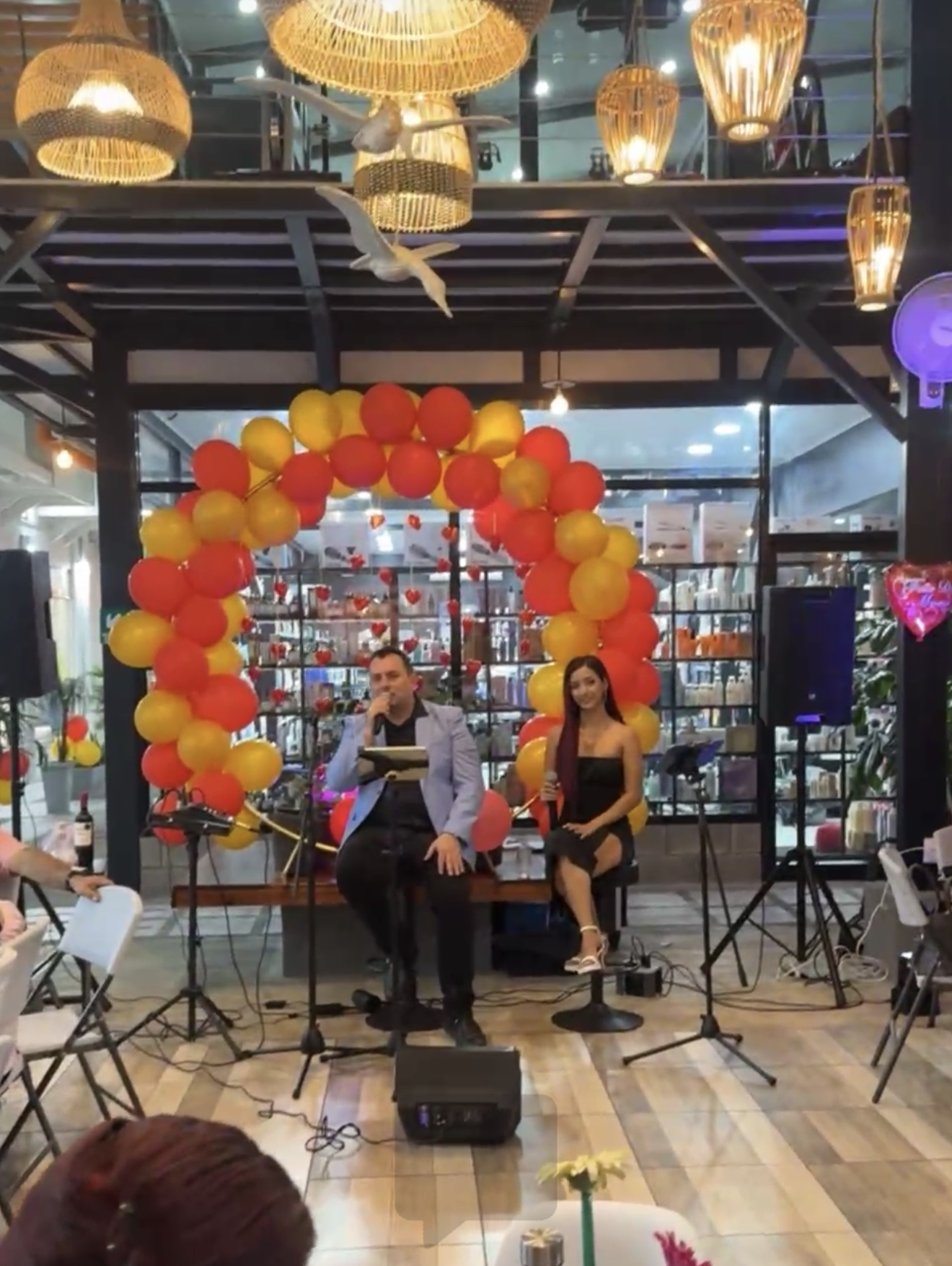 SKALA interpretando en vivo bajo un arco de globos en un restaurante